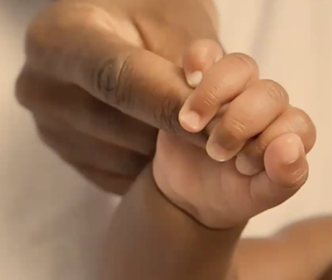 newborn holding mother's finger